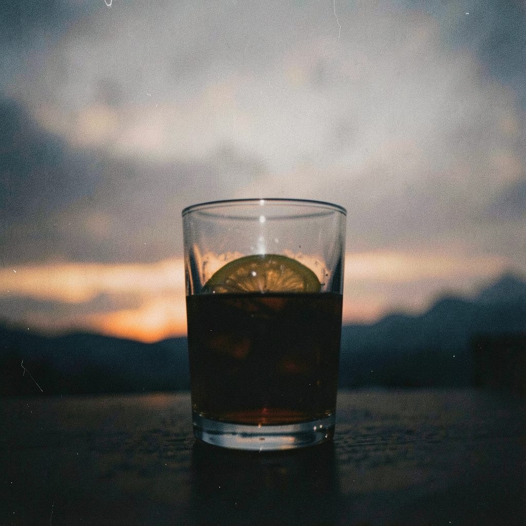 Segelas rum gelap dengan latar langit malam Miami, warna amber tua dan biru tua, foto film bergrain