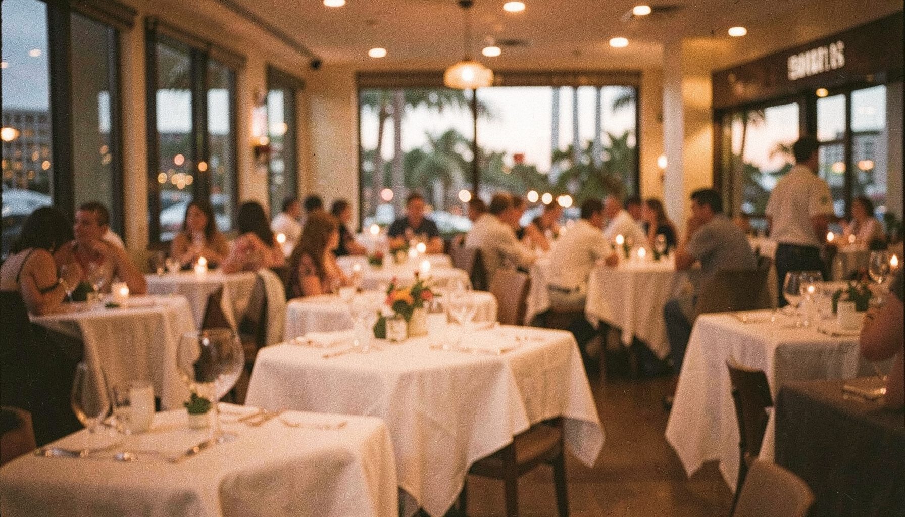 Ruang makan restoran Miami yang hangat saat senja dengan pencahayaan amber lembut dan meja-meja tertata rapi